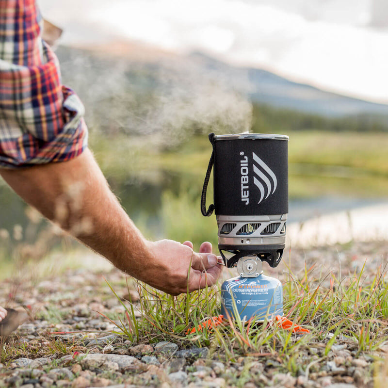 Man adjusting the temperature on the Jetboil MicroMo on a rocky terrain