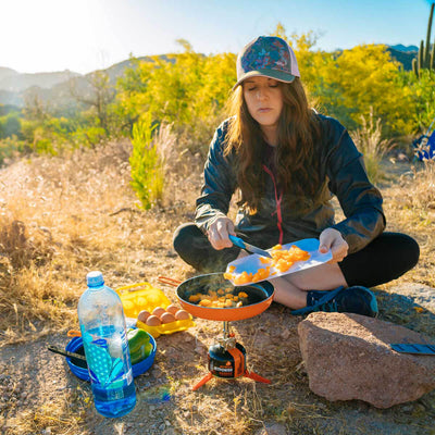 Women cooking with the Jetboil MightyMo sitting down on the ground