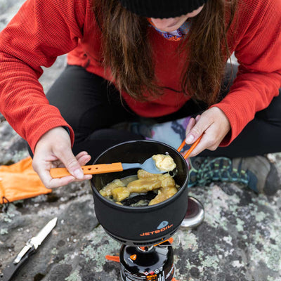 Women eating out of the Jetboil 1.5L Ceramic FluxRing Cook Pot on a rock